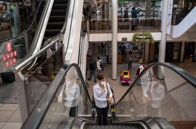 A woman use the escalator inside a shopping centre during its reopening after the outbreak of coronavirus, COVID-19, in Santiago.