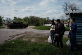 People watch a Ukrainian tank driving on a road after receiving packages from a food distribution in Rai-Oleksandrivka, eastern Ukraine, on April 29, 2022, amid Russia's military invasion launched on Ukraine. (Photo by Yasuyoshi CHIBA / AFP) (Photo by YASUYOSHI CHIBA/AFP via Getty Images)