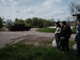 People watch a Ukrainian tank driving on a road after receiving packages from a food distribution in Rai-Oleksandrivka, eastern Ukraine, on April 29, 2022, amid Russia's military invasion launched on Ukraine. (Photo by Yasuyoshi CHIBA / AFP) (Photo by YASUYOSHI CHIBA/AFP via Getty Images)