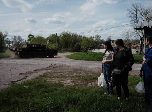 People watch a Ukrainian tank driving on a road after receiving packages from a food distribution in Rai-Oleksandrivka, eastern Ukraine, on April 29, 2022, amid Russia's military invasion launched on Ukraine. (Photo by Yasuyoshi CHIBA / AFP) (Photo by YASUYOSHI CHIBA/AFP via Getty Images)