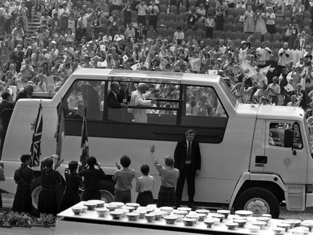 Pope John Paul II waves from the Popemobile as he makes his way through a welcoming crowd at Bellahouston Park.