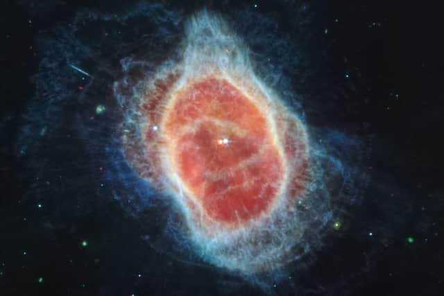 This image from the James Webb Space Telescope has revealed the cloak of dust around the second star, shown at left in red, at the center of the Southern Ring Nebula for the first time.  (Photo by Handout / NASA / AFP)