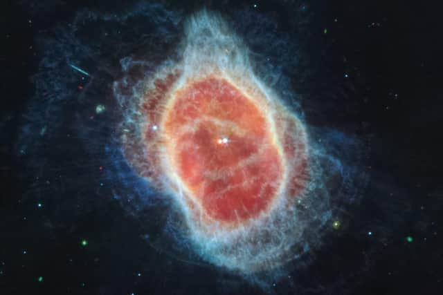 This image from the James Webb Space Telescope has revealed the cloak of dust around the second star, shown at left in red, at the center of the Southern Ring Nebula for the first time. (Photo by Handout / NASA / AFP)