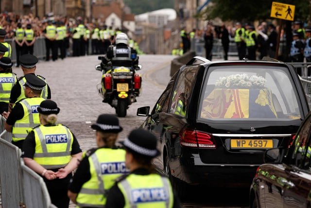 The hearse carrying the coffin of Queen Elizabeth II, draped in the Royal Standard of Scotland, is driven through Edinburgh towards the Palace of Holyroodhouse