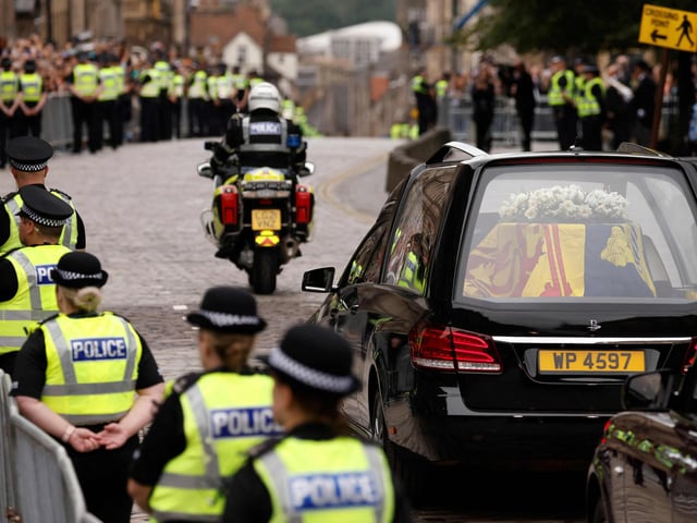 The hearse carrying the coffin of Queen Elizabeth II, draped in the Royal Standard of Scotland, is driven through Edinburgh towards the Palace of Holyroodhouse