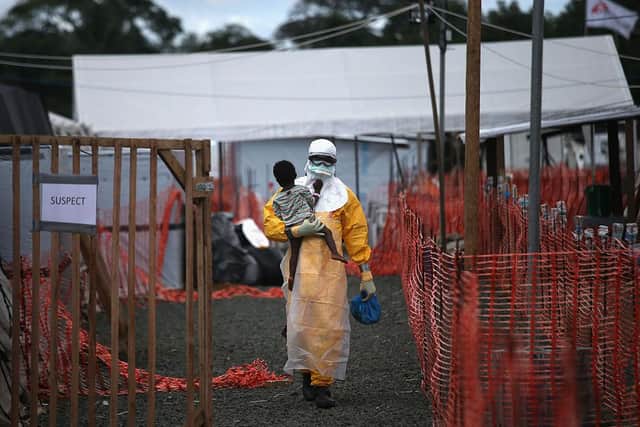 A health worker in protective clothing carries a child suspected of having Ebola in October 2014 in Liberia (Photo: John Moore/Getty Images)