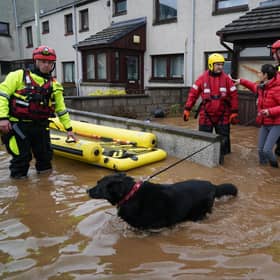 A member of the emergency services helps resident Laura Demontis from a house in Brechin, Scotland, as Storm Babet batters the country. (Credit: Andrew Milligan/PA Wire)