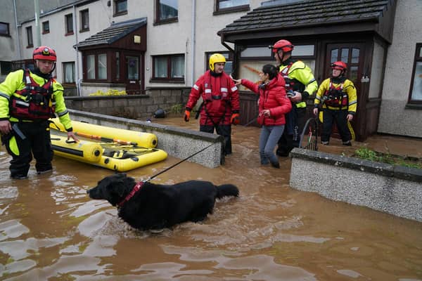 A member of the emergency services helps resident Laura Demontis from a house in Brechin, Scotland, as Storm Babet batters the country. (Credit: Andrew Milligan/PA Wire)
