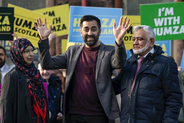 Humza Yousaf waves as he stands with his mother Shaaista and father Muzaffar during an event at Pollockshields Burgh Hall as he campaigns to become the next leader of the Scottish National Party. Photo by Jeff J Mitchell/Getty Images