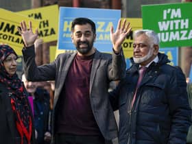 Humza Yousaf waves as he stands with his mother Shaaista and father Muzaffar during an event at Pollockshields Burgh Hall as he campaigns to become the next leader of the Scottish National Party. Photo by Jeff J Mitchell/Getty Images