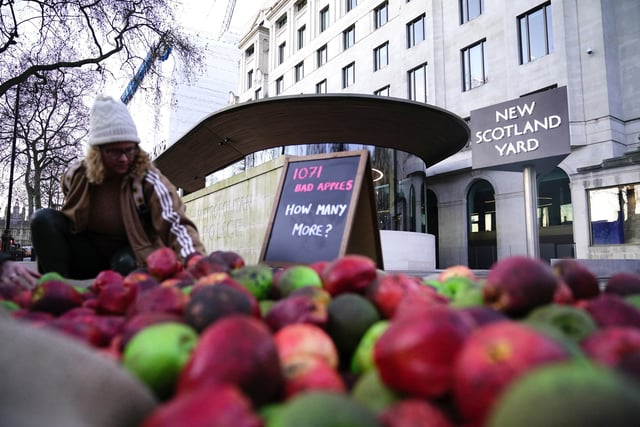 A person helps to place 1,071 rotten apples outside New Scotland Yard. Police have received more calls after rapist officer David Carrick was exposed as being one of the UK’s most prolific known sex offenders. Aaron Chown/PA Wire