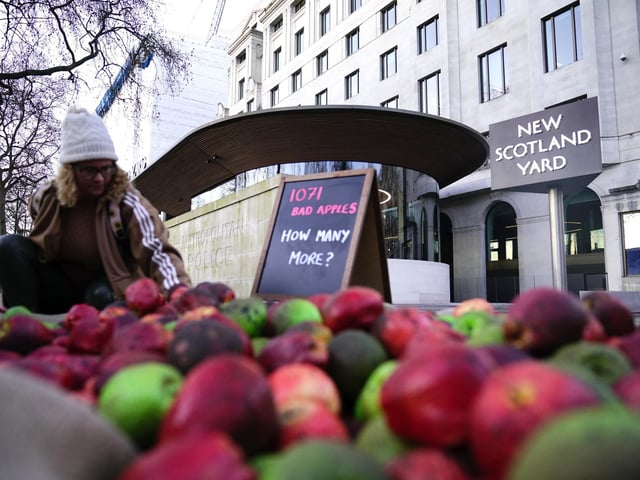 A person helps to place 1,071 rotten apples outside New Scotland Yard. Police have received more calls after rapist officer David Carrick was exposed as being one of the UK’s most prolific known sex offenders. Aaron Chown/PA Wire