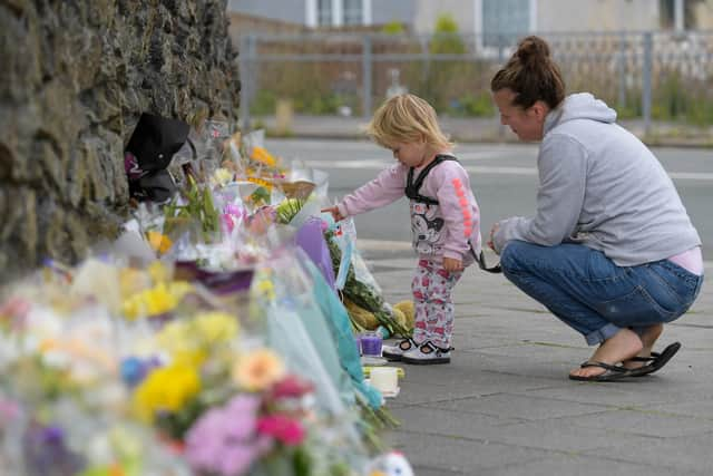 PLYMOUTH, ENGLAND - AUGUST 16: A woman and child look at the flowers and tributes left at Keyham on August 16, 2021 in Plymouth, England.  (Photo by Finnbarr Webster/Getty Images)