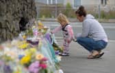 PLYMOUTH, ENGLAND - AUGUST 16: A woman and child look at the flowers and tributes left at Keyham on August 16, 2021 in Plymouth, England.  (Photo by Finnbarr Webster/Getty Images)