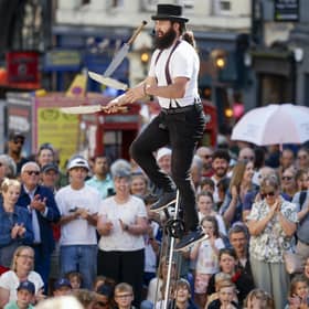 A big Fringe crowd watches a performer juggleswith knives while balancing on a giraffe unicycle on Edinburgh's High Street (Picture: Jeff J Mitchell/Getty Images)