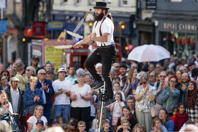 A big Fringe crowd watches a performer juggleswith knives while balancing on a giraffe unicycle on Edinburgh's High Street (Picture: Jeff J Mitchell/Getty Images)