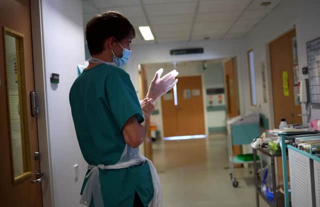A junior doctor gets ready for his shift. (Photo by HANNAH MCKAY/POOL/AFP via Getty Images)
