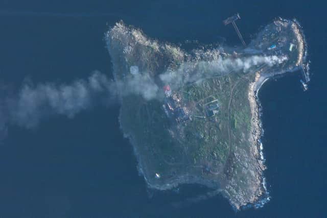 This satellite image taken by Planet Labs PBC shows smoke rising after Ukrainian strikes destroyed buildings housing Russian positions and a helicopter on Snake Island in the Black Sea Sunday, May 8, 2022. (Planet Labs PBC via AP)