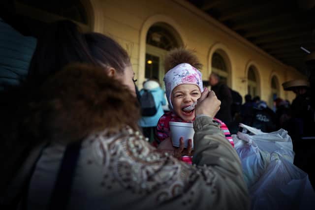 A young child from Ukraine is given some food as she waits with her family and their luggage at Przemysl train station in Poland. Picture date: Saturday March 19, 2022.