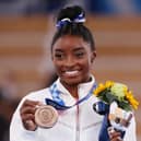 Simone Biles ssmile as she poses with the bronze medal after the beam final