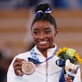 Simone Biles ssmile as she poses with the bronze medal after the beam final