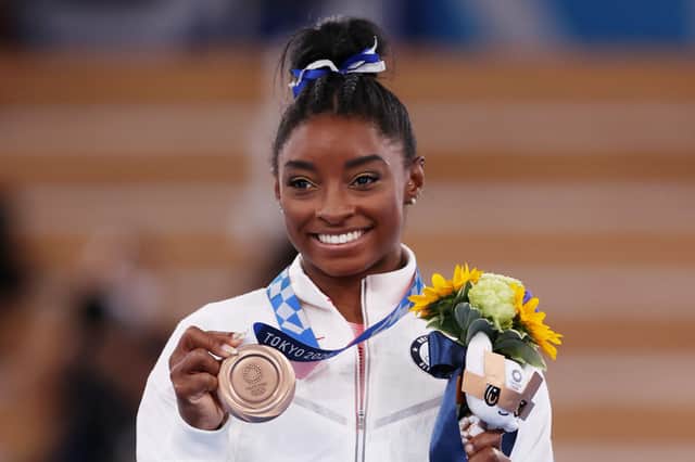 Simone Biles ssmile as she poses with the bronze medal after the beam final