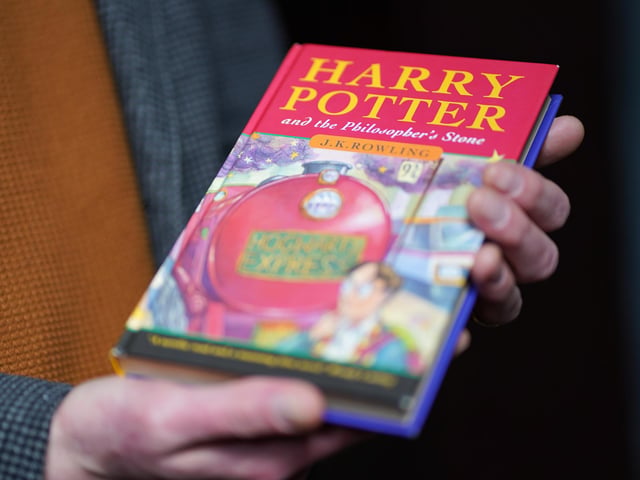 Auctioneer Jim Spencer holds a pristine first edition hardback of JK Rowling's Harry Potter and the Philosopher's Stone, one of only 500 produced in the first print run in 1997 22.