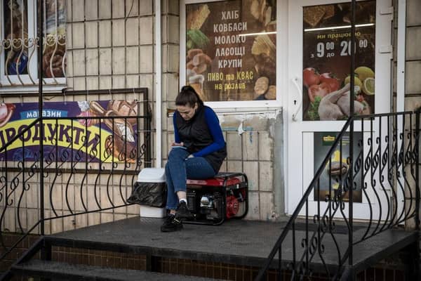 A woman sits on a generator outside a shop in Borodyanka in the Kyiv region, Ukraine. Picture: Getty Images