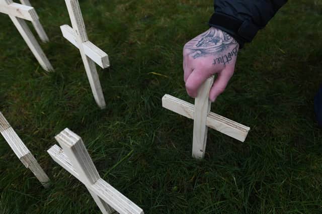 A man leaves a cross for his brother in Glasgow. Favor Scotland has planted 200 crosses on Valentine’s Day for drug death victims. Picture: John Devlin