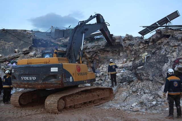 White Helmet Syrian rescue workers use an excavator to search amidst the rubble of collapsed building on February 6, 2022 in the town of Sarmada, in Syria's rebel-held northwestern Idlib province, as a search operation continues following a deadly earthquake. - At least 1,400 people were killed and 3,411 injured across Syria today in an earthquake that had its epicentre in southwestern Turkey, the government and rescuers said. (Photo by AAREF WATAD / AFP) (Photo by AAREF WATAD/AFP via Getty Images)