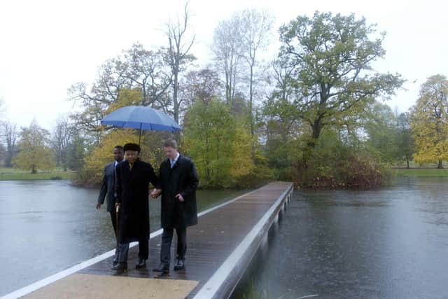 Former South African president Nelson Mandela (centre), Earl Spencer (right) and an aide walk, across a pontoon from the island where Diana, Princess of Wales, is buried at her ancestral home at Althorp in Northamptonshire.  *   Mandela was planting a tree in the grounds of the estate and laying a wreath at the island burial site, during the visit to discuss a new charity project with Diana's brother Earl Spencer.