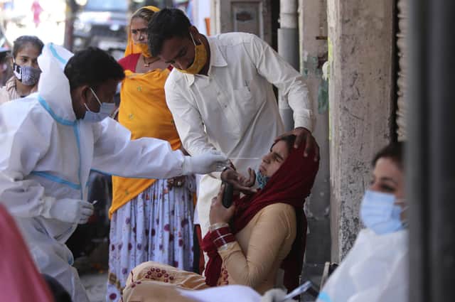 A health worker takes a nasal swab sample to test for coronavirus in Jammu, India, where authorities are scrambling to get medical oxygen to hospitals where COVID-19 patients are suffocating from low supplies. (AP Photo/Channi Anand)