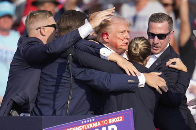 Donald Trump is surrounded by US Secret Service agents as he is helped off the stage at the campaign rally. Picture: Gene J. Puskar/AP