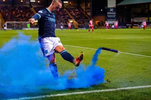 Dundee's Leigh Griffiths kicks a blue smoke bomb back into the stand housing St Johnstone fans. (Photo by Ross Parker / SNS Group)