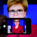 A person uses their phone to film a televised broadcast of First Minister Nicola Sturgeon. Picture: PA