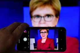 A person uses their phone to film a televised broadcast of First Minister Nicola Sturgeon. Picture: PA