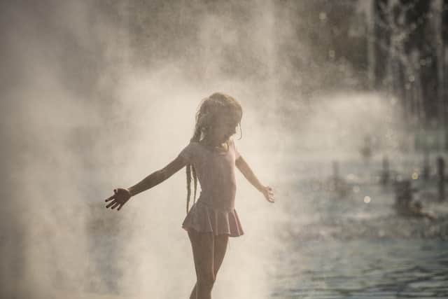 A girl enjoys the cooling mist from a public fountain in Bucharest, Romania,. Picture: AP Photo/Alexandru Dobre