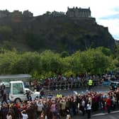 The Popemobile drives down Princes Street with Edinburgh Castle in the background.