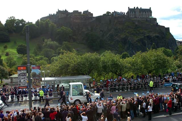 The Popemobile drives down Princes Street with Edinburgh Castle in the background.