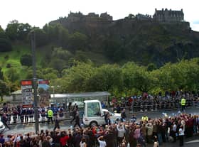 The Popemobile drives down Princes Street with Edinburgh Castle in the background.