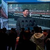 Visitors walk in front of a screen showing China's President Xi Jinping at the Museum of the Communist Party of China in Beijing (Picture: Noel Celis/AFP via Getty Images)