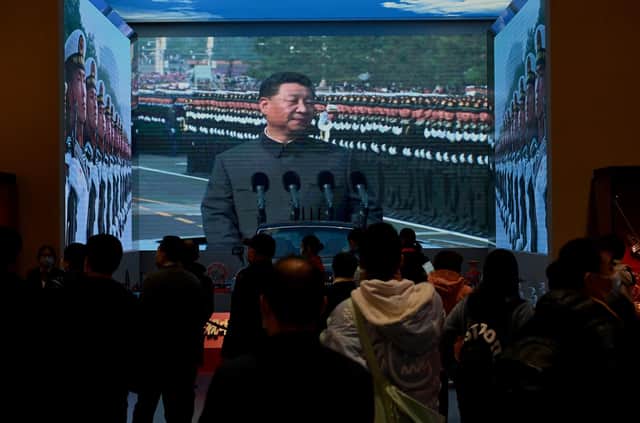Visitors walk in front of a screen showing China's President Xi Jinping at the Museum of the Communist Party of China in Beijing (Picture: Noel Celis/AFP via Getty Images)