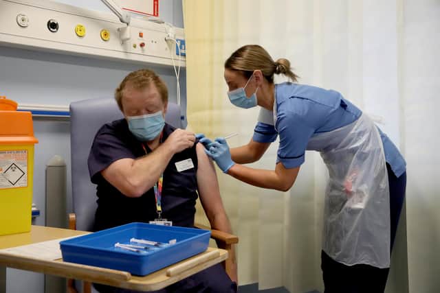Deputy charge nurse Katie McIntosh administers the first of two Pfizer/BioNTech Covid-19 vaccine jabs to Clinical Lead of Outpatient Theatres Andrew Mencnarowski, at the Western General Hospital, in Edinburgh, on the first day of the largest immunisation programme in the UK's history.