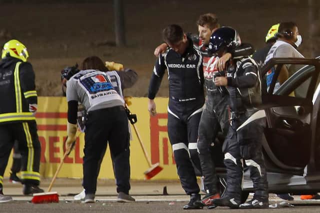 Stewards and medics attend to Romain Grosjean after his crash at the start of the Bahrain Grand Prix.