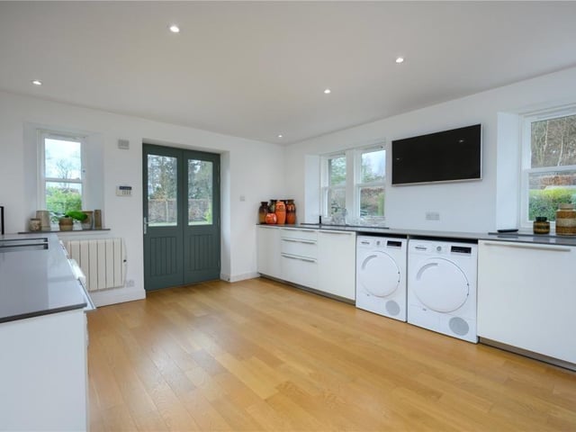 Utility room with fitted cabinets, television, and a door to the parking area.