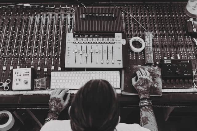 "Composing in the Shadows: A music producer reviews her session in a dimly lit studio — part of the growing workforce behind the fully owned audio economy."