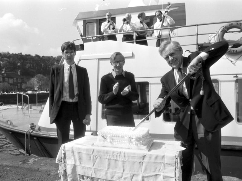 Journalist, author and TV presenter Magnus Magnusson cuts the cake to celebrate the commissioning of the Maid of the Forth passenger ferry at the Firth of Forth, May 1988.