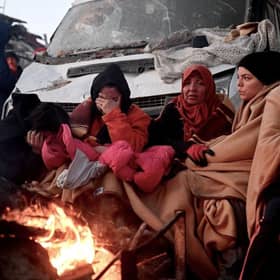 People sit near a bonfire amidst the rubble of collapsed buildings in Kahramanmaras, two days after a 7,8-magnitude earthquake struck southeast Turkey.