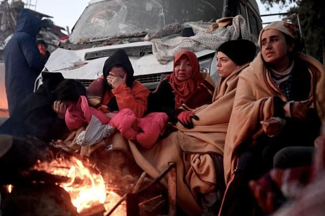 People sit near a bonfire amidst the rubble of collapsed buildings in Kahramanmaras, two days after a 7,8-magnitude earthquake struck southeast Turkey.