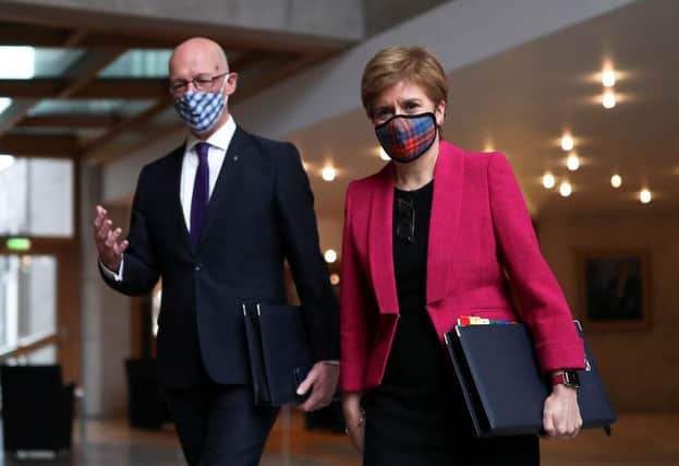 John Swinney, seen with Nicola Sturgeon, tests himself for Covid every time he leaves the house and is going to be in contact with other people (Picture: Russell Cheyne/pool/AFP via Getty Images)